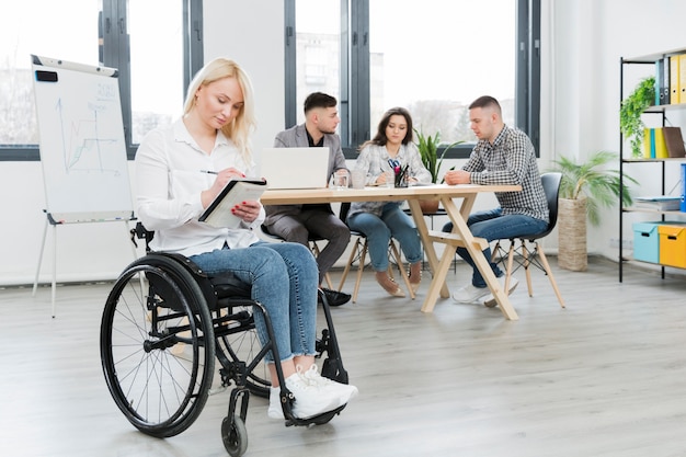 Vista lateral de la mujer en silla de ruedas en la oficina