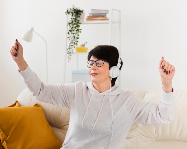 Vista lateral de la mujer en el sofá disfrutando de la música en los auriculares