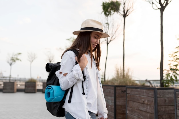 Vista lateral de la mujer con sombrero y mochila mientras viaja