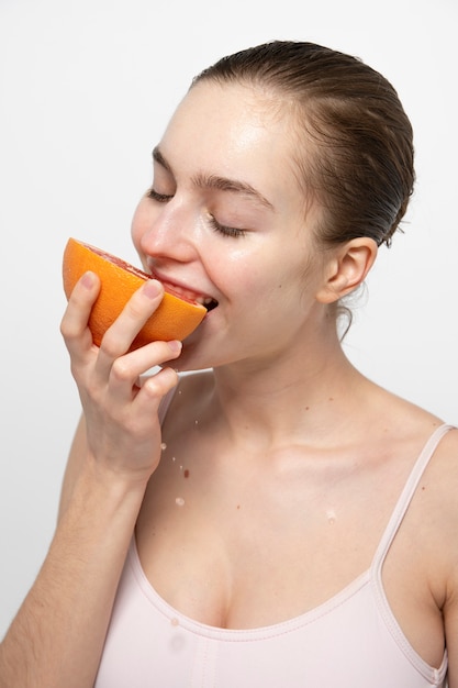 Vista lateral mujer sonriente comiendo pomelo