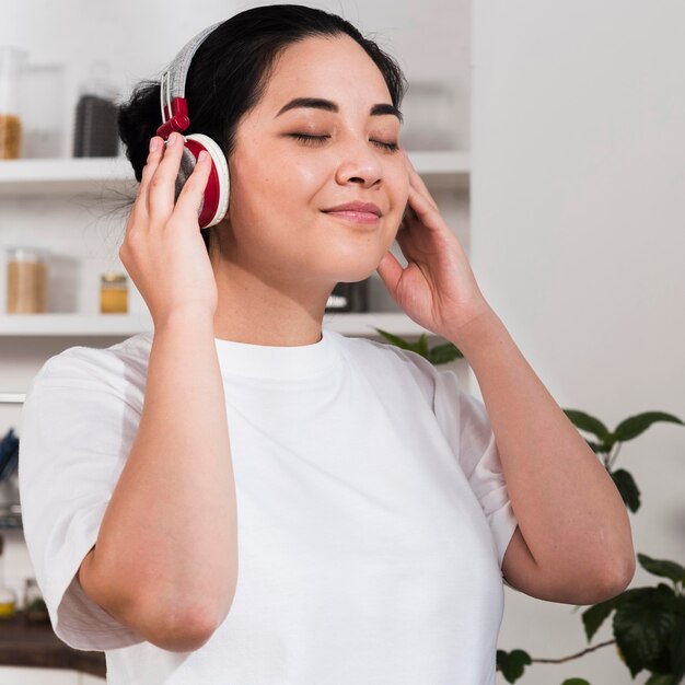 Vista lateral de la mujer sonriente disfrutando de la música en auriculares