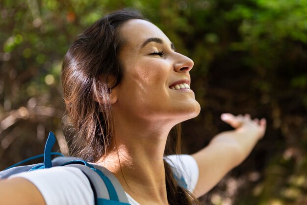Vista lateral de la mujer sonriente disfrutando de su exploración de la naturaleza