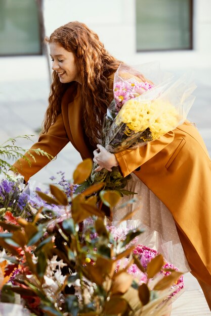 Vista lateral de la mujer sonriente eligiendo ramo de flores de primavera