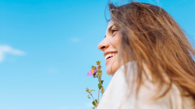 Vista lateral de la mujer sonriente con espacio de copia y flor