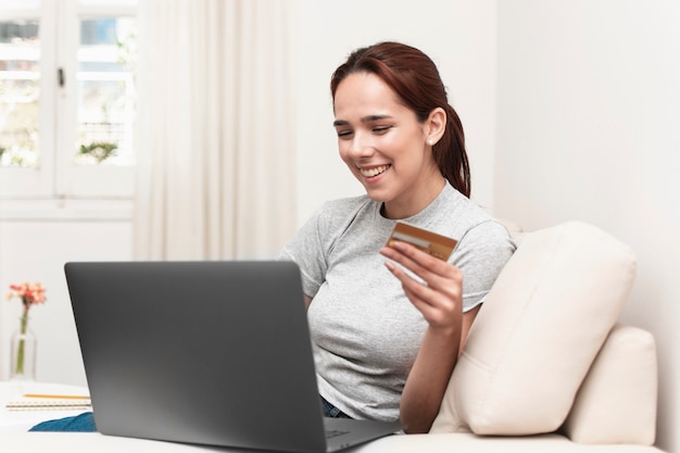 Vista lateral de la mujer sonriente con laptop y tarjeta de crédito