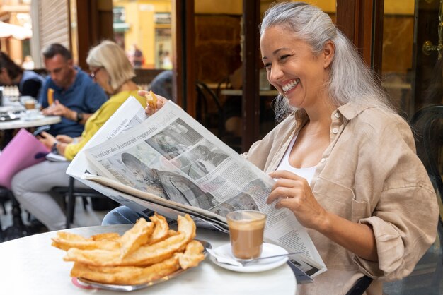 Vista lateral mujer sonriente leyendo el periódico