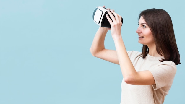 Vista lateral de la mujer sonriente mirando a través del casco de realidad virtual