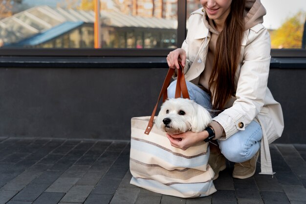 Vista lateral mujer sonriente con perro en bolsa
