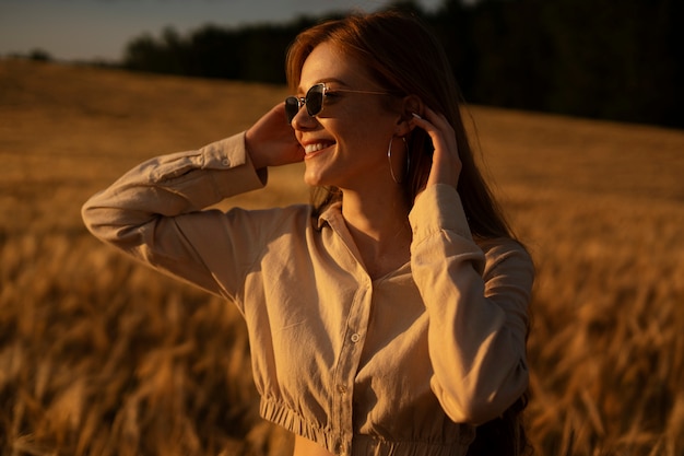 Vista lateral mujer sonriente posando con gafas de sol