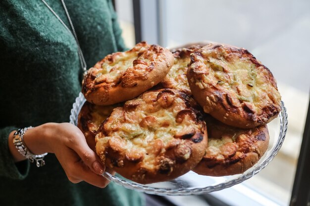 Vista lateral mujer sostenga una bandeja de mini pizzas con salchichas