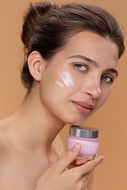 Vista lateral mujer sosteniendo envase de crema facial