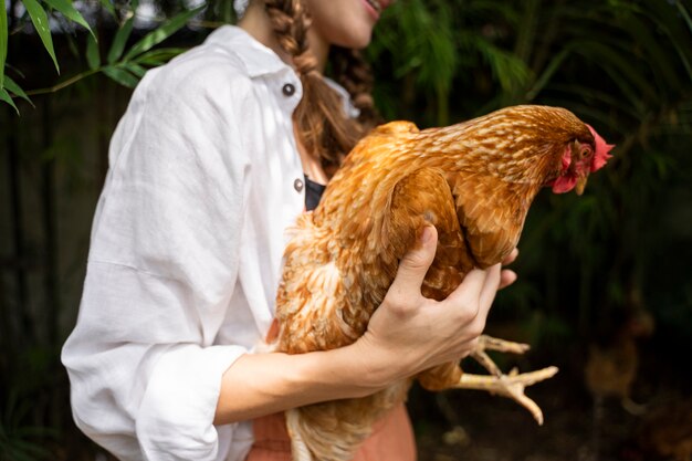 Vista lateral mujer sosteniendo gallina