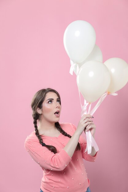 Vista lateral de la mujer sosteniendo y mirando y globos