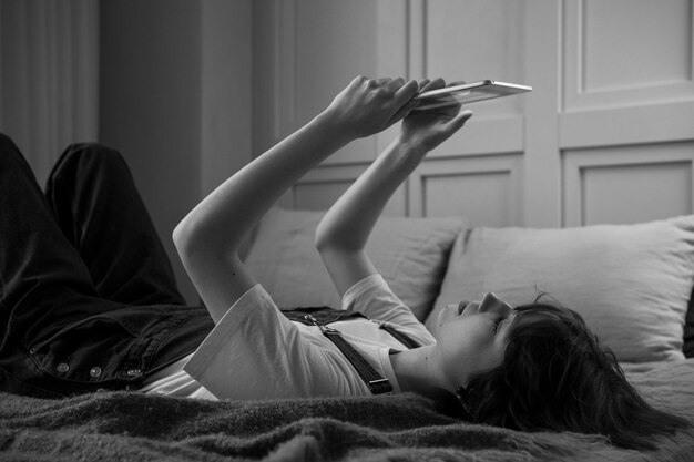 Vista lateral mujer con tableta en la cama