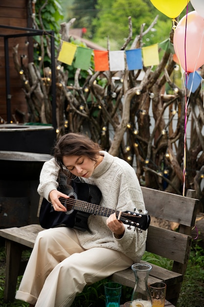 Vista lateral mujer tocando la guitarra al aire libre