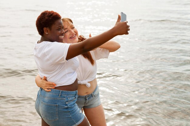 Vista lateral de la mujer tomando selfie en la playa.