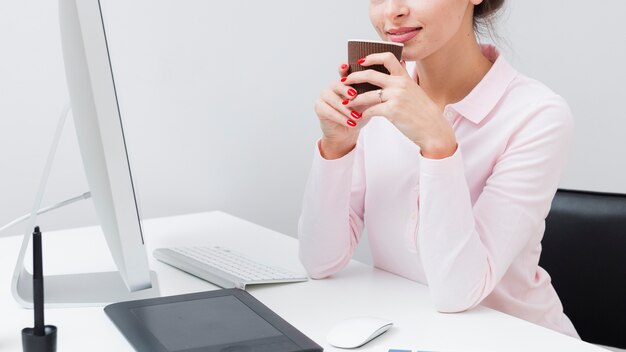 Vista lateral de la mujer trabajadora en el escritorio con una taza de café