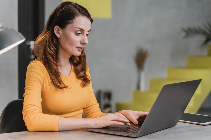 Foto gratuito vista lateral de una mujer trabajando en una computadora portátil