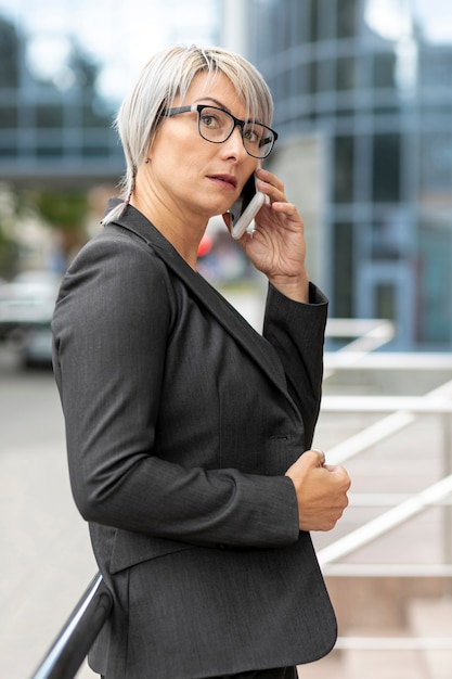 Foto gratuita vista lateral mujer en traje hablando por teléfono