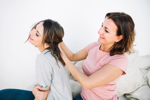 Vista lateral mujer trenzando cabello de mujer