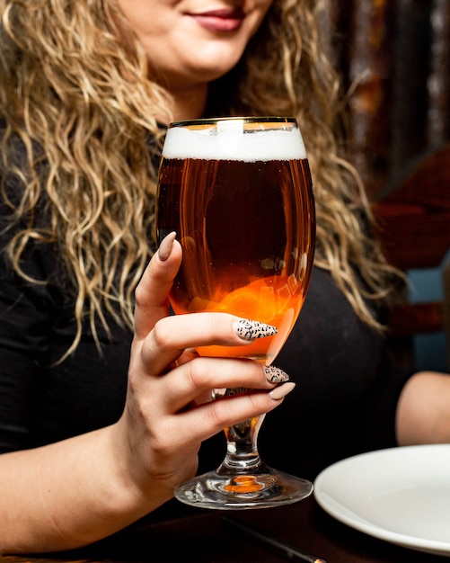 Vista lateral de una mujer con un vaso de cerveza