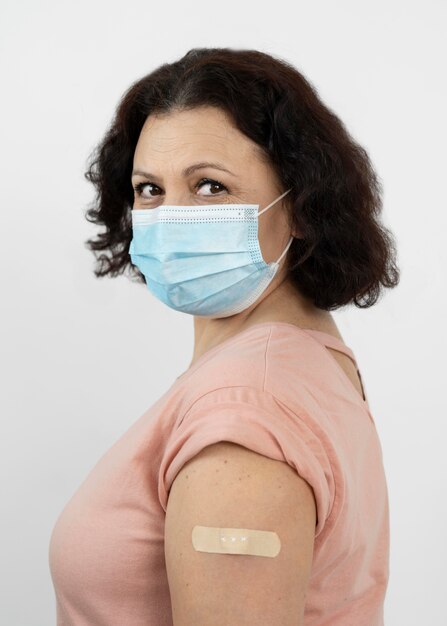 Vista lateral de la mujer con vendaje en el brazo después de la inyección de la vacuna