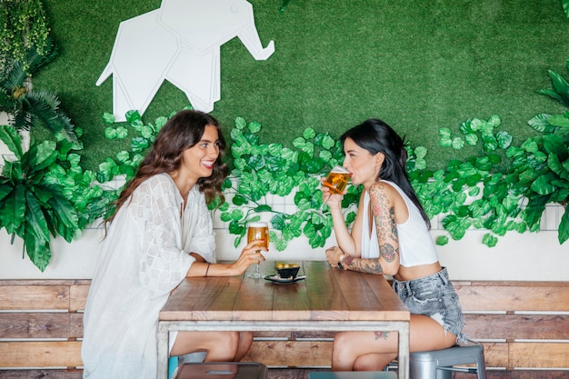 Vista lateral de mujeres bebiendo cerveza en mesa