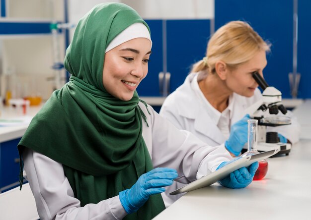 Vista lateral de mujeres científicas en el laboratorio trabajando juntas