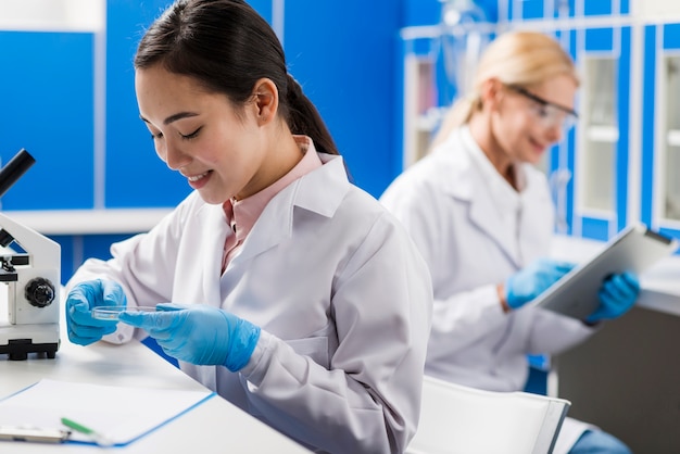 Vista lateral de las mujeres científicas sonrientes que trabajan en el laboratorio