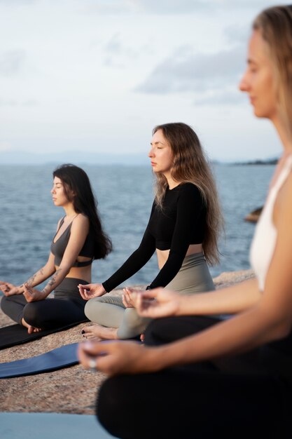 Vista lateral de mujeres jóvenes meditando en estera