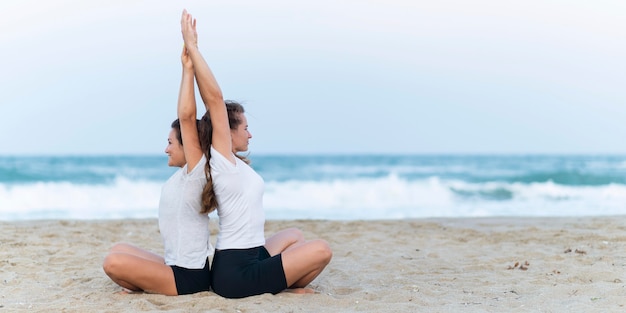 Vista lateral, de, mujeres, practicar, yoga, en la playa