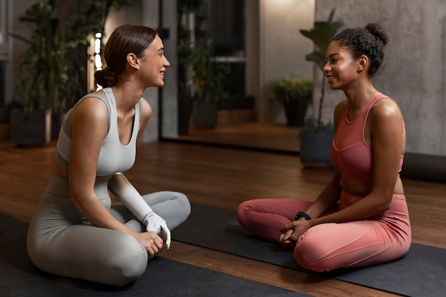 Vista lateral de mujeres sonrientes en colchonetas de yoga
