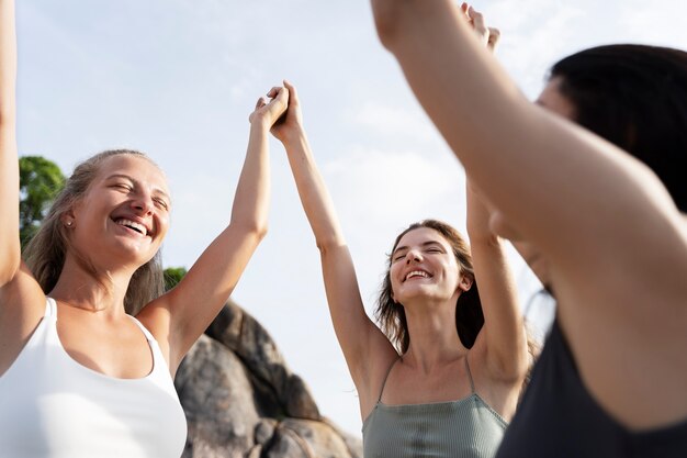 Vista lateral de mujeres sonrientes tomados de la mano al aire libre