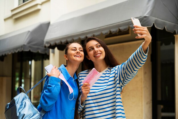 Vista lateral de mujeres sonrientes tomando selfie