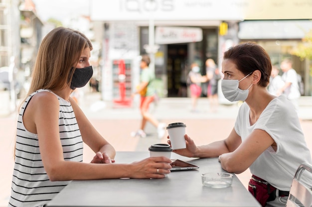 Foto gratuita vista lateral de las mujeres en la terraza con máscaras