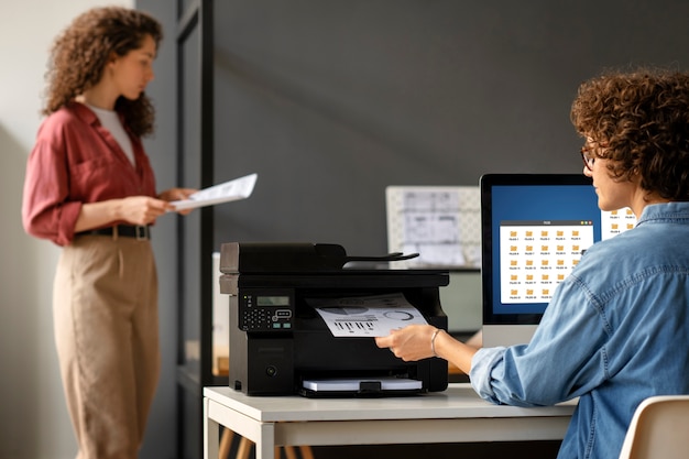 Vista lateral de mujeres usando impresora en el trabajo