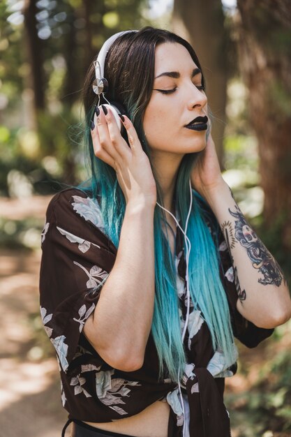 Vista lateral de una música que escucha joven moderna de la mujer en el auricular blanco