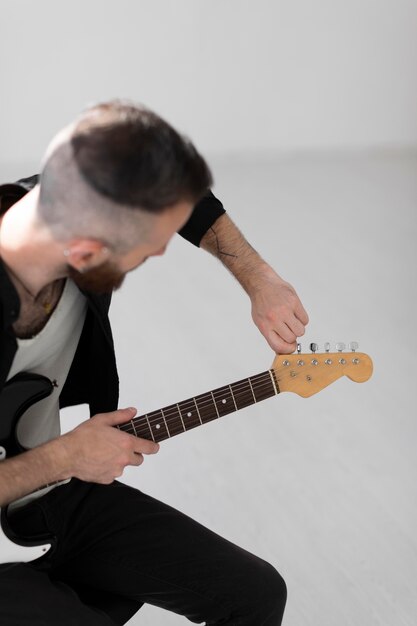 Vista lateral del músico masculino tocando la guitarra eléctrica