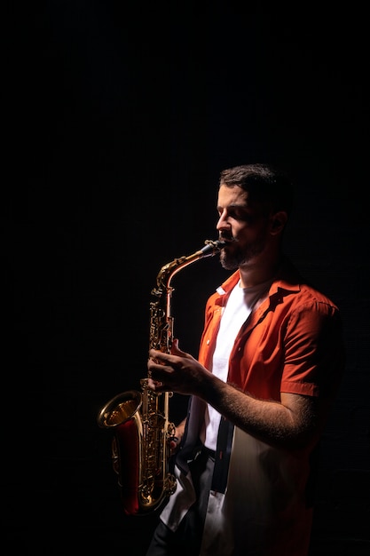 Vista lateral del músico tocando el saxofón con espacio de copia