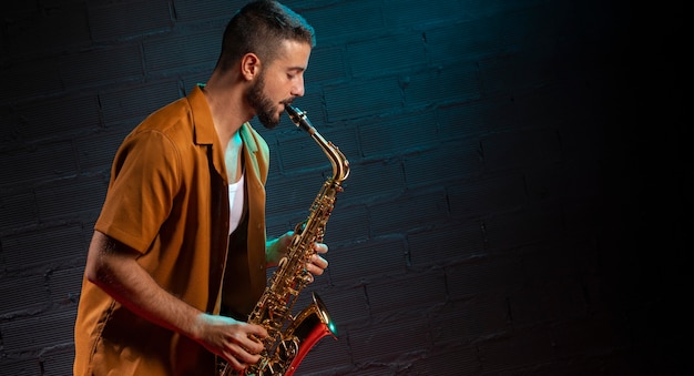 Vista lateral del músico tocando el saxofón en foco con espacio de copia