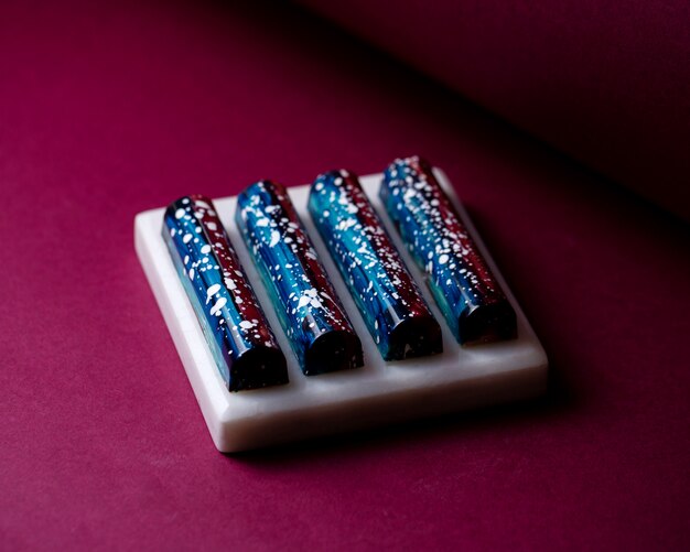 Vista lateral negro y azul en blanco moteado dulces de chocolate en soporte blanco