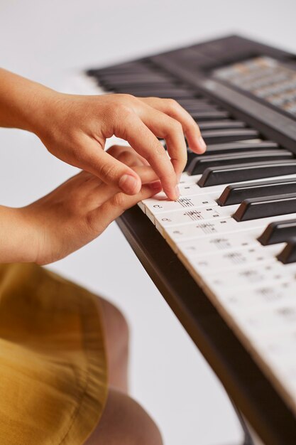 Vista lateral de la niña aprendiendo a tocar el teclado electrónico