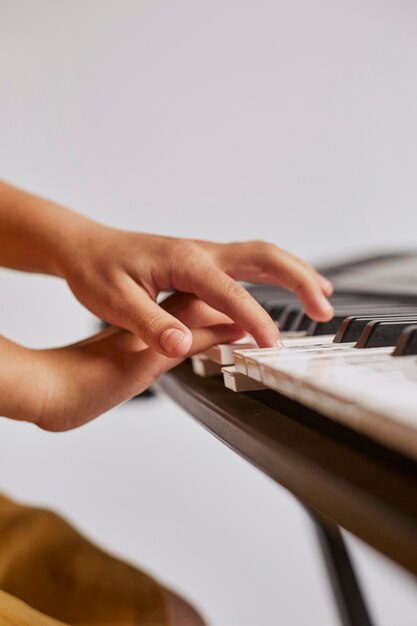 Vista lateral de la niña aprendiendo a tocar el teclado electrónico