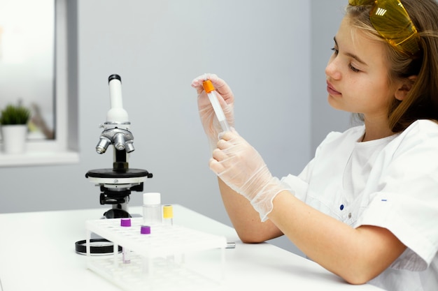 Foto gratuita vista lateral de la niña científica con gafas de seguridad y microscopio