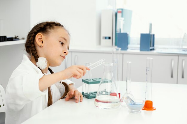 Vista lateral de la niña científica en el laboratorio con tubos de ensayo