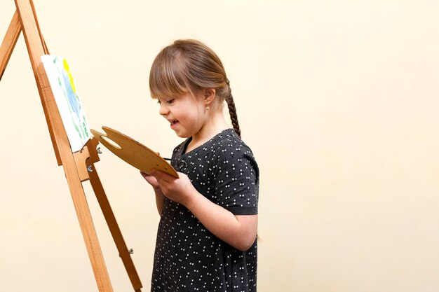 Vista lateral de la niña feliz con pintura de síndrome de down