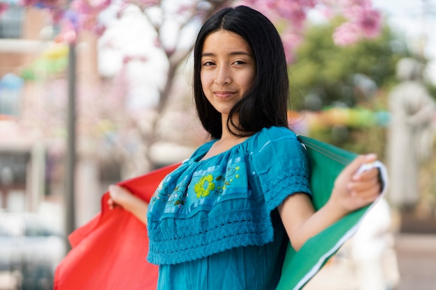 Vista lateral niña sonriente con bandera mexicana