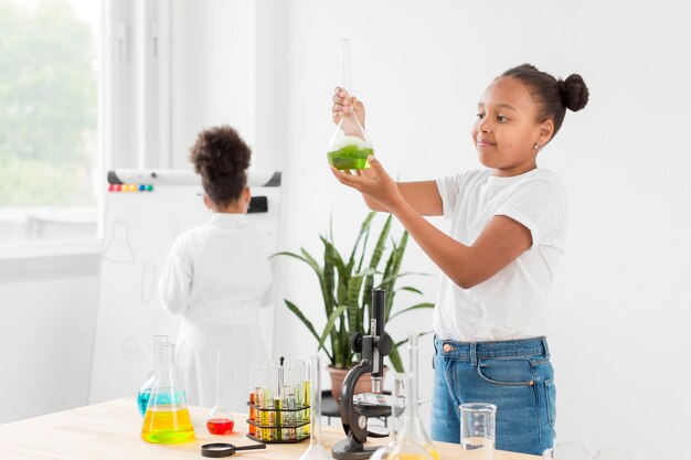 Vista lateral de la niña sosteniendo el tubo de ensayo con poción