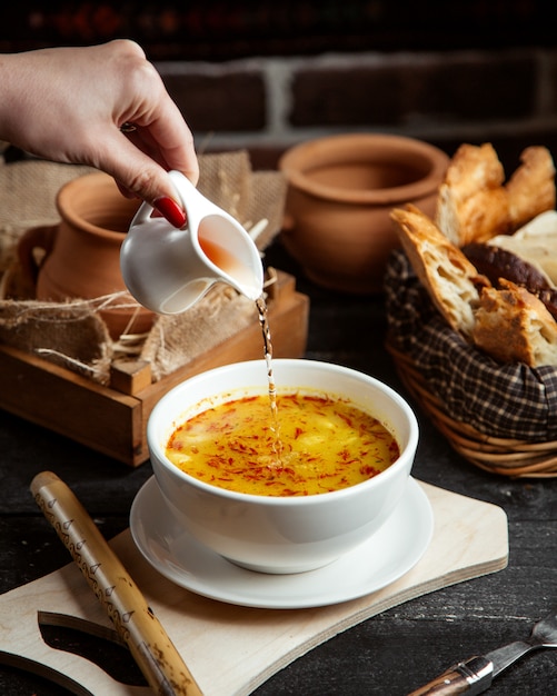 Vista lateral, una niña vierte vinagre en un plato sopa dushbara un plato tradicional azerbaiyano