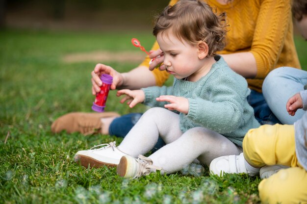 Vista lateral del niño al aire libre en el parque con madres lgbt